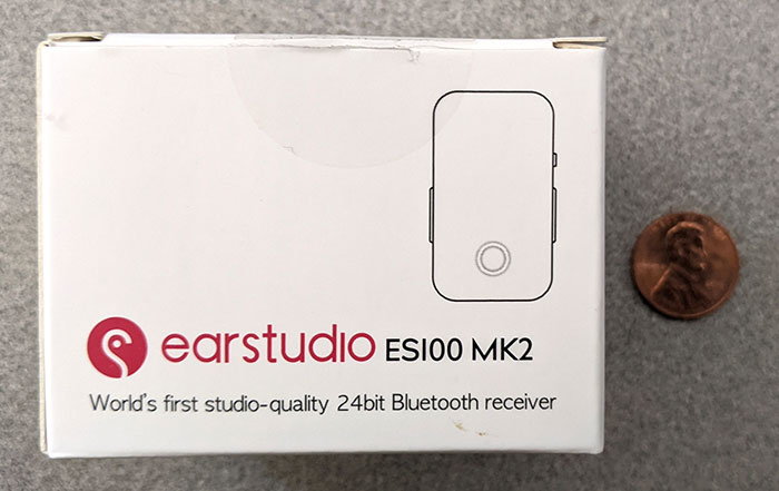 Earstudio ES100 MK2蓝牙接收器盒的正面照片，上面有一便士作为刻度