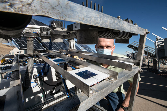 研究人员在NREL室外测试设施检查光伏板的污染检测器单元的照片